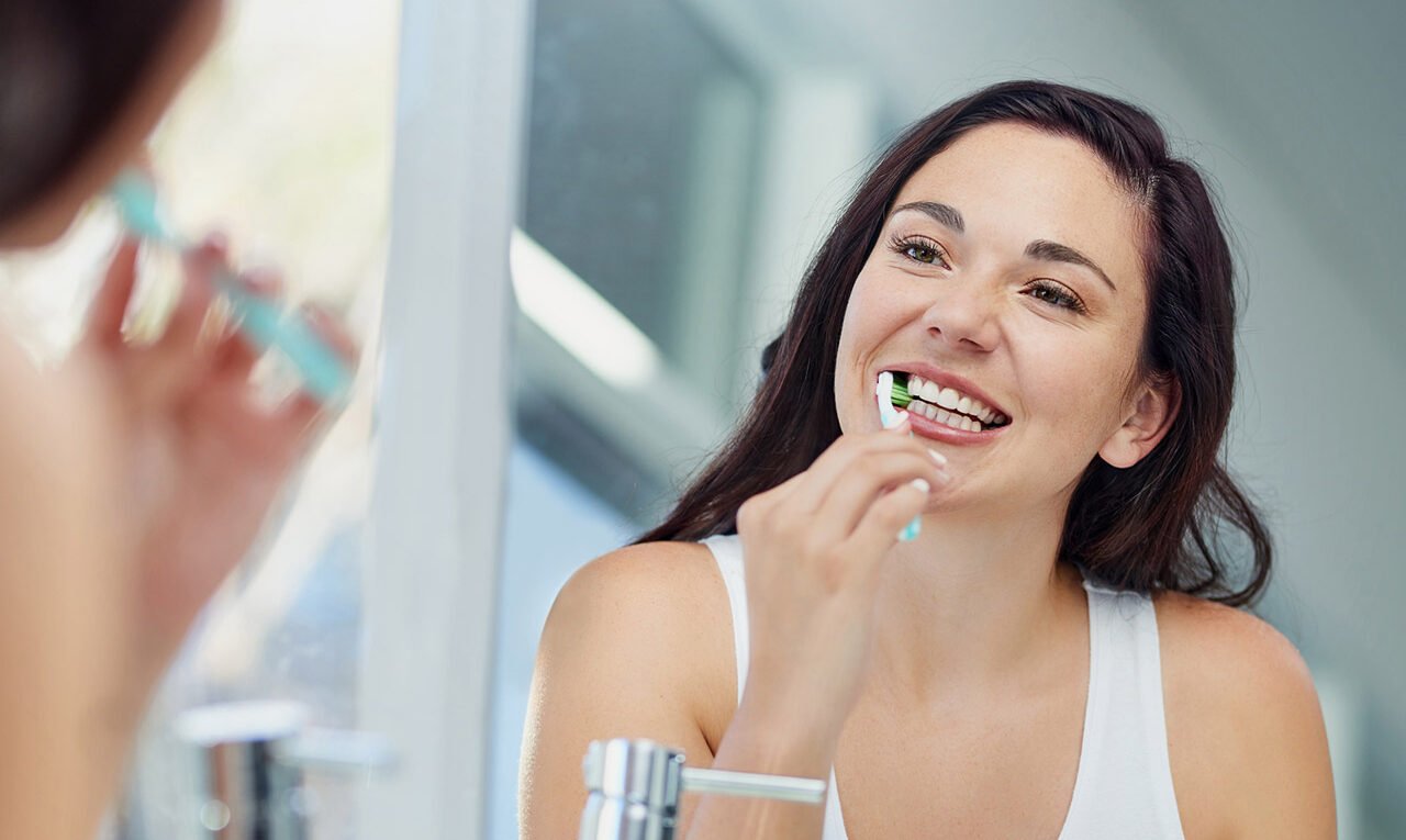Smiling woman showing essential care to keep teeth strong and healthy.